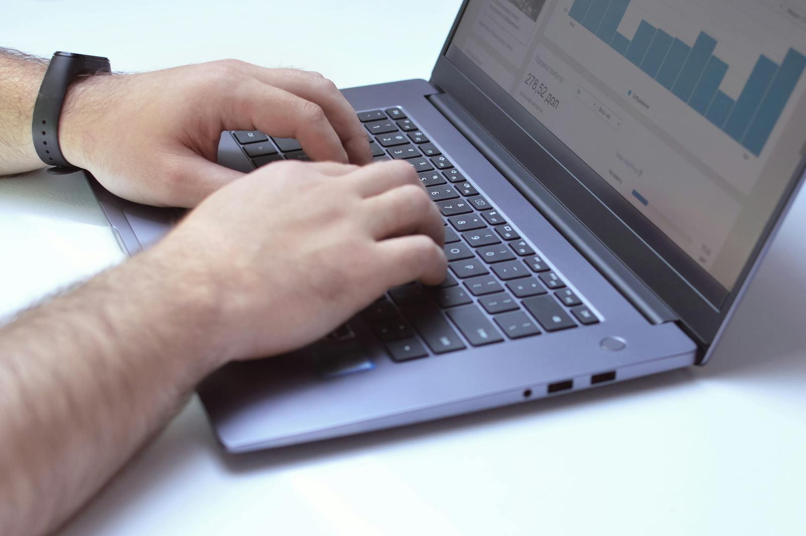 Close-up of hands typing on a laptop displaying data analysis charts, perfect for business contexts.