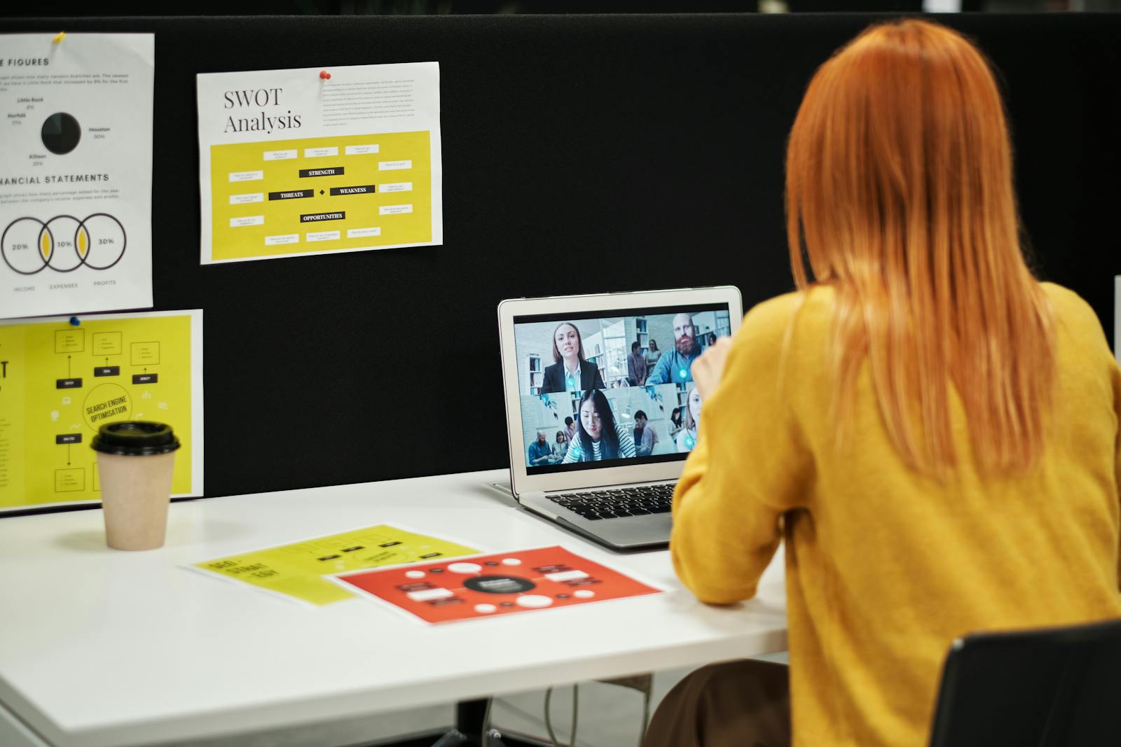 Businesswoman conducts virtual meeting via laptop at her office desk.