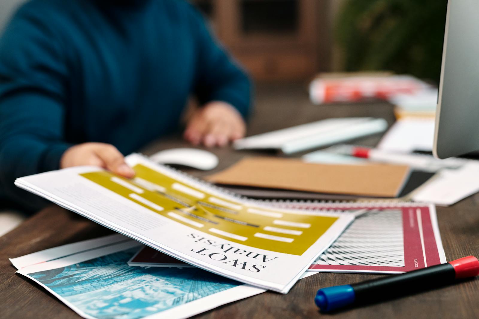 A person examines a SWOT analysis paper on a desk, focused on business strategy and planning.